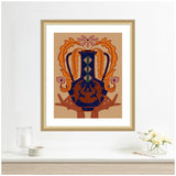 Framed print featuring a stylized symmetrical design with bold burnt orange shapes, deep blue center pattern, and hands at the bottom on a tan background.