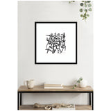 Black abstract intersecting lines and shapes on white background in a black square frame, hanging above a wooden table with neutral decor and green hanging plant.