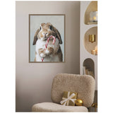 Framed canvas of a brown and white bunny holding a red and white striped candy cane, hung on a beige wall above a textured beige chair with gold-wrapped gift and ornament.