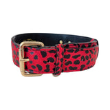 Red leather collar with black leopard print pattern and gold metal buckle, shown coiled with visible stitching detail and leather loop.