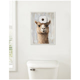 Framed canvas painting of a brown alpaca head with a white toilet paper roll balanced on its head, hung above a white toilet tank against a pale wall.