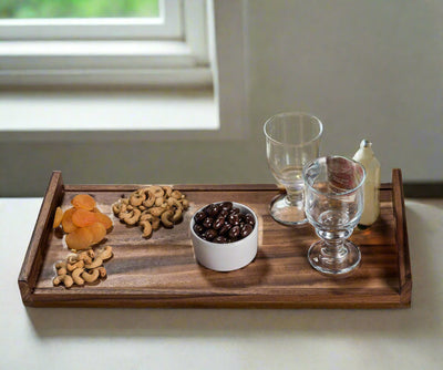 Kalmar Home solid Acacia wood Long Serving Tray shown on tabletop with decorative items