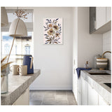 Muted floral painting with beige, brown, and navy flowers on a white wall in a bright kitchen with gray countertops and white cabinets.