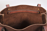 Interior view of a brown suede leather tote with a smooth leather strip secured by four brass rivets near the top edge.
