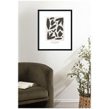 Framed abstract floral print titled 'Les Fleurs' with black organic shapes on a beige background, hanging above an olive green chair and a woven basket plant.
