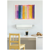 Abstract framed canvas with vertical vibrant lines in purple, blue, orange, yellow, and pink hues hanging above a white desk with a wooden chair, pencils in a black cup, and a small wooden toy car.