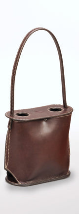 Tall brown leather wine tote with two circular openings on top, featuring white stitching and a rigid handle looped from the base.