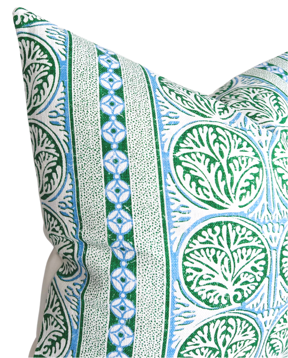 Close-up of a pillow cover with a Fair Isle pattern featuring repeating green circular leaf motifs and vertical blue and green geometric stripes on a white background.