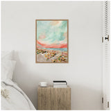 A framed abstract landscape painting with pastel shades of turquoise, coral, and beige hangs on a white wall above a rustic wooden side table holding a white cup and stacked books.