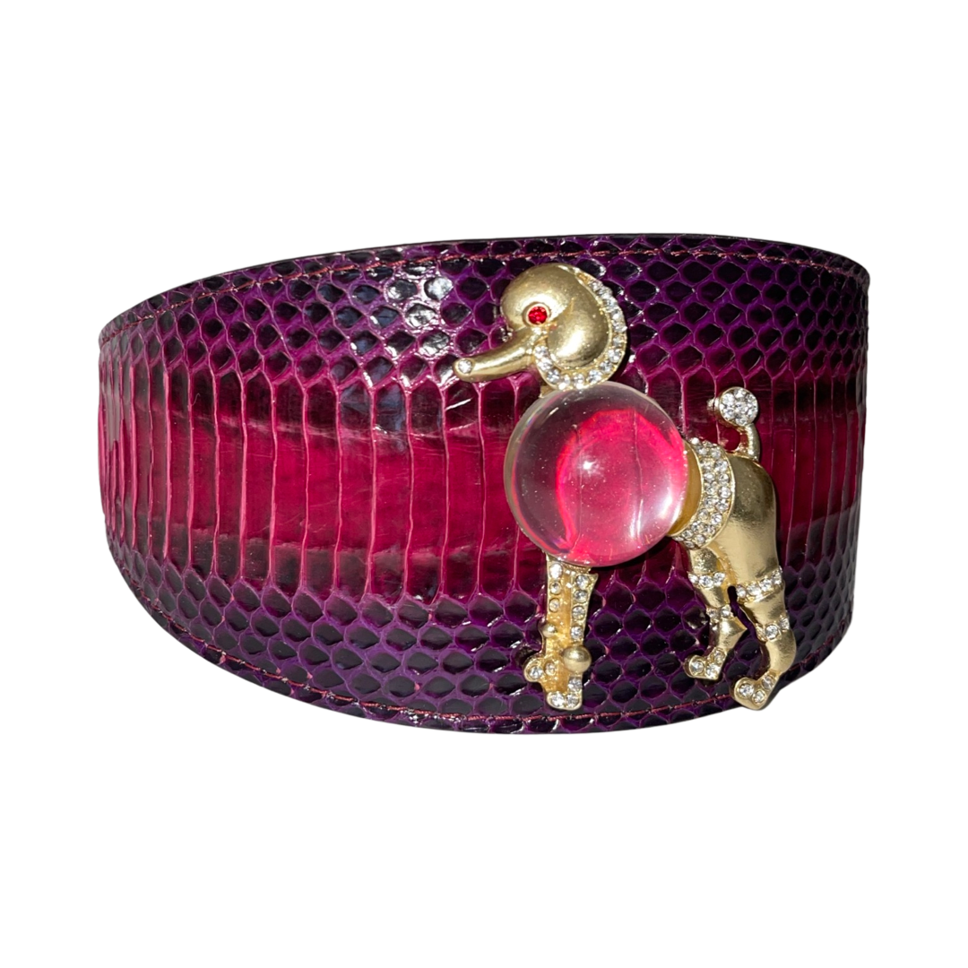 Purple and pink snakeskin-patterned dog collar featuring a gold-tone poodle ornament with a red jewel eye, crystal accents, and a translucent pink resin body.