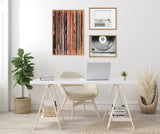 Minimalist workspace with white desk and beige chair beneath three framed canvases: vertical colorful record spines, a black and white record player sketch, and a close-up of vinyl on turntable.