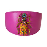 Bright pink leather dog collar featuring a large jeweled beetle with multicolored stones and intricate detailing at the center.