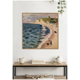 Framed Henri Matisse 1920 painting of a curving beach with blue-green sea, sandy shore, cliffs, and small figures under a cloudy sky, hung above a wooden console table.