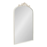 Tall arched mirror with a cream-colored frame featuring ornate floral carving at the top center and smooth edges along the sides.