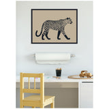 Framed linocut-style print of a black-spotted leopard silhouette on a tan background, hung above a white desk with wooden chair and toys.