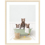 Three brown bear cubs sitting and standing in a light green clawfoot bathtub with a white towel draped over the side, a wicker basket nearby, and a yellow rubber duck on a beige rug beneath them.
