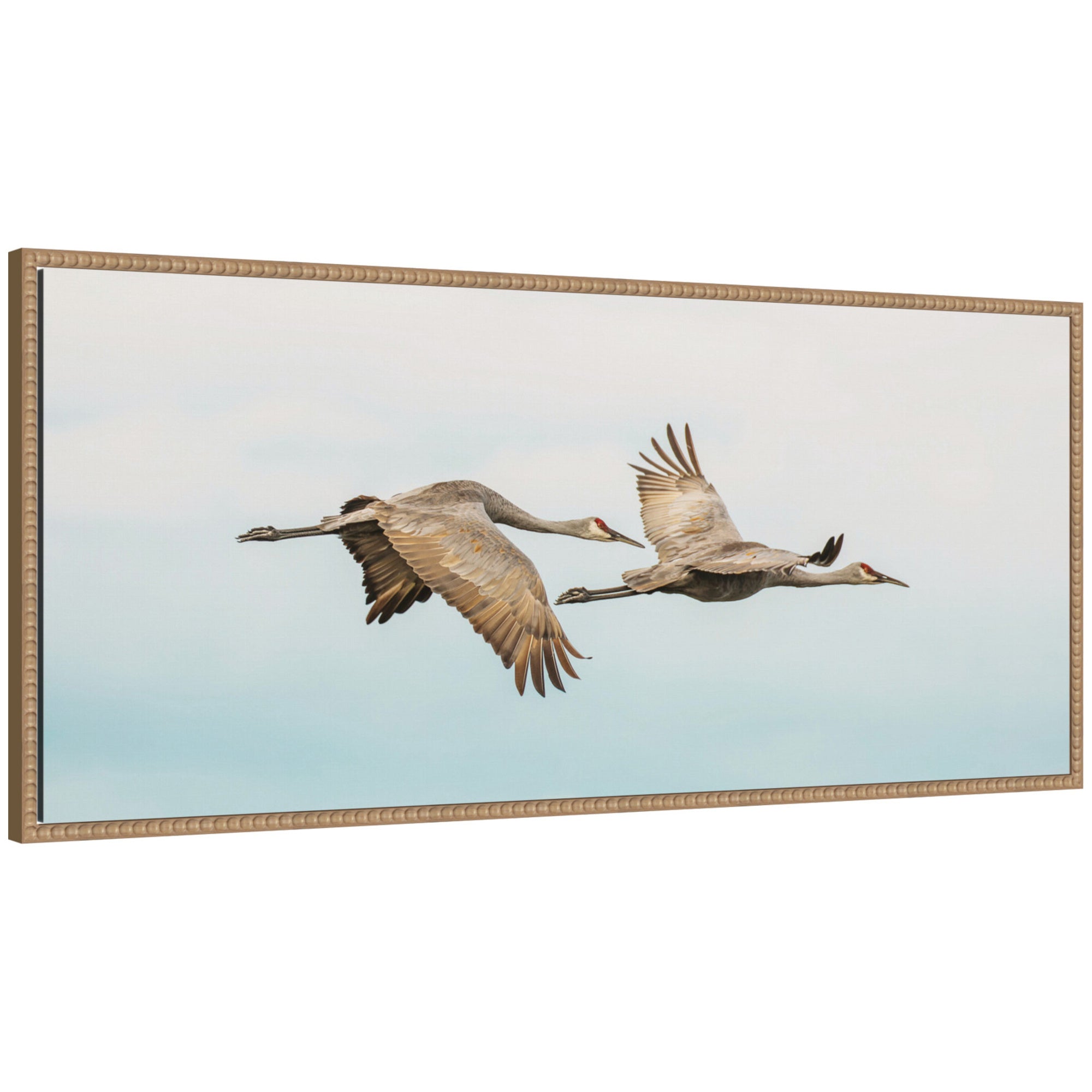 Framed canvas wall art depicting two cranes flying against a pale sky, set in a beaded rustic natural wood frame.