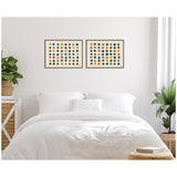 Two framed canvases each featuring a grid of multicolored dots in a neutral-toned bedroom above a white bed with pillows and flanked by green plants in woven baskets.