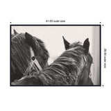 Black and white close-up of two black horses with bridles, one facing forward and the other turned slightly, highlighting their manes and ears.