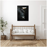 Close-up portrait of a black Highland cow with textured fur and one visible horn, set against a dark background on a framed canvas print above a wooden bench.