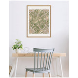 Framed William Morris Windrush 1883 botanical print with intricate green and beige floral patterns, hanging above a minimal wooden desk with a plant and blue chair.