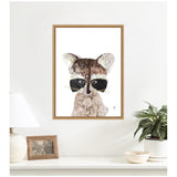 Framed canvas print of a stylized raccoon with textured brown and grey fur, prominent black eye patches, and white background, hanging above a white shelf.