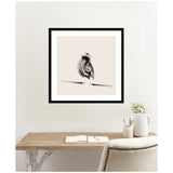 Black and gray artistic sketch of a bird perched on a branch, framed with a black border, hanging above a wooden desk with minimal decor.