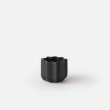 Small black matte ceramic planter with scalloped edges and vertical ridges, shown against a plain white background.