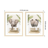 Two framed prints showing an elephant in a white clawfoot bathtub with green palm leaves and a beige rug, one with the elephant facing front and the other from behind.