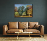 Framed canvas painting of an autumn forest with colorful trees in green, yellow, orange, and red tones hanging above a tan leather sofa in a dark teal room.