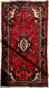 Hand-knotted Persian Hamadan wool rug with a deep red field, intricate floral and geometric motifs, and a contrasting cream-colored central medallion.