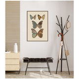 Framed vintage butterfly print with six butterflies in muted earth tones, hanging on a light wall above a black cushioned bench and beside a tall black coat rack with hat and umbrellas.