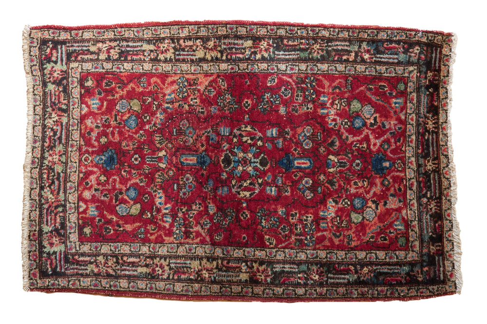 Rectangular vintage Lilihan rug mat with a deep red field featuring intricate floral and geometric patterns in blue, cream, and black, framed by a multi-layered ornate border.