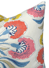 Corner of a fabric pillow cover featuring a floral print with coral and yellow flowers and blue leaves on a white background.