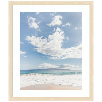 Framed Art Beach by Alicia Abla showing a calm beach with gentle waves, an island on the horizon under a partly cloudy blue sky.