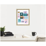 Framed print collage of colorful matchbook designs including teal Aquarius label and stylized illustrations, hanging above a white desk with books, plant, open notebook, and mug.