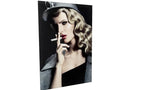 Black-and-white portrait of a woman with curled blonde hair and red lipstick, wearing a hat and a coat, smoking a cigarette against a dark background.