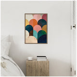 Framed geometric abstract art with overlapping jewel-toned semicircles in orange, teal, pink, navy, yellow, and cream on a neutral wall above a rustic wooden side table.