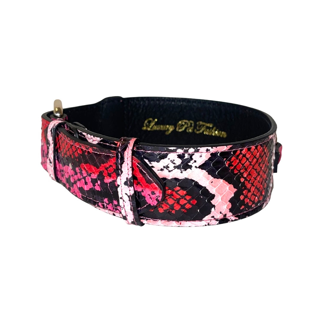 Dog collar with red, black, fuchsia, and light pink snakeskin pattern and black inner lining, shown angled against white background