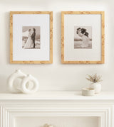 Two square wooden picture frames with natural burl wood grain, each holding a black-and-white photo of a bride and groom, displayed above a white mantel with minimalist vases.
