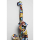 Colorful wall-hanging ape sculpture with elongated arm raised, featuring swirling patterns of blue, red, yellow, and white across its body and face, viewed frontally.