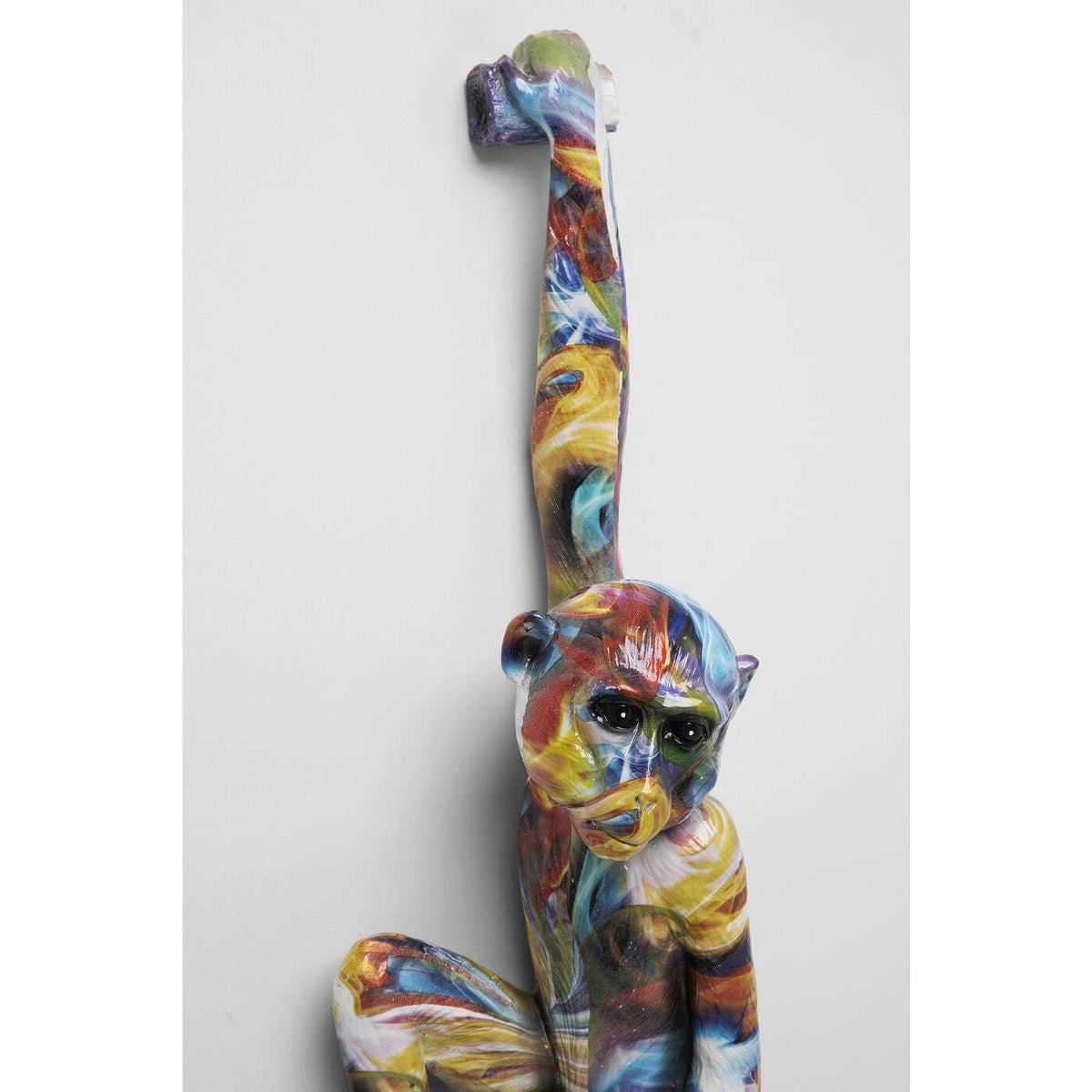 Colorful wall-hanging ape sculpture with elongated arm raised, featuring swirling patterns of blue, red, yellow, and white across its body and face, viewed frontally.