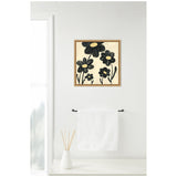 Framed canvas artwork featuring black flowers with yellow centers on an off-white background, hanging above a white towel on a black rod in a minimalist bathroom setting.