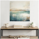 Abstract landscape painting with soft blue and beige tones depicting a calm lake and distant hills, framed and hung above a minimalist wood and metal table.