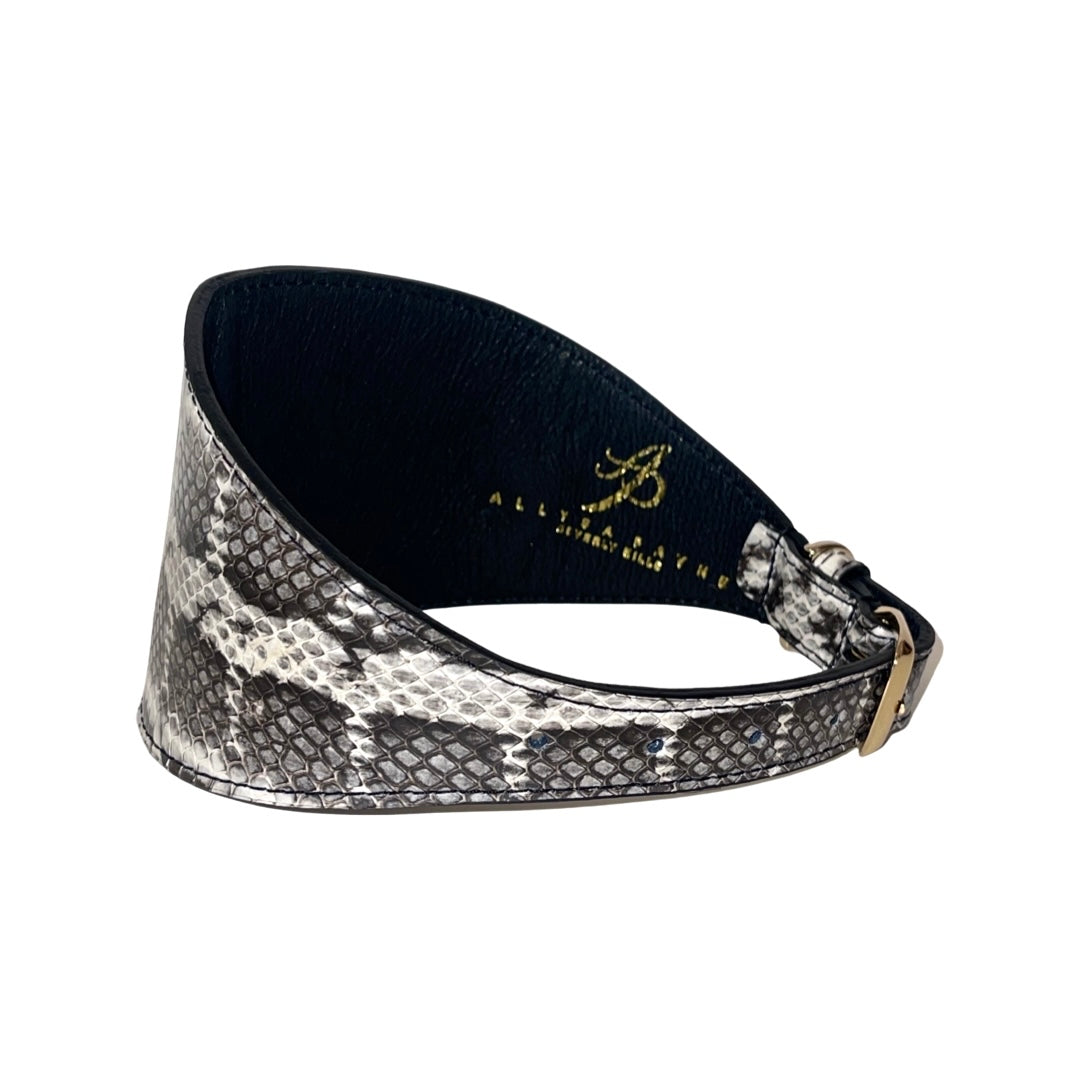 Wide collar with white and black snake-patterned texture and a gold buckle, shown curved with smooth black inner lining and gold embossed branding inside.