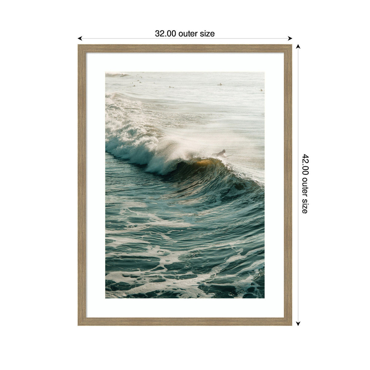 Framed print of a turquoise ocean wave cresting with white foam and soft golden sunlight reflecting off the water, bordered by a neutral wood frame.