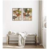 Two framed canvas prints with abstract botanical design in earth tones, hanging above a wooden bench with an open book and draped beige fabric in a minimalist room.