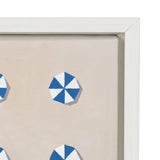Close-up of a framed canvas artwork showing blue and white geometric pinwheel shapes on a beige background with a white wooden frame.