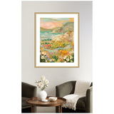 Framed abstract landscape painting with pastel pink, green, and yellow hues depicting hills and wildflowers, hanging above a cozy seating area with olive chairs and a wooden table.