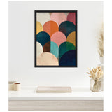 Framed canvas with overlapping semi-circles in jewel tones including navy, teal, blush pink, orange, and gold, displayed above a white tabletop with neutral decor.